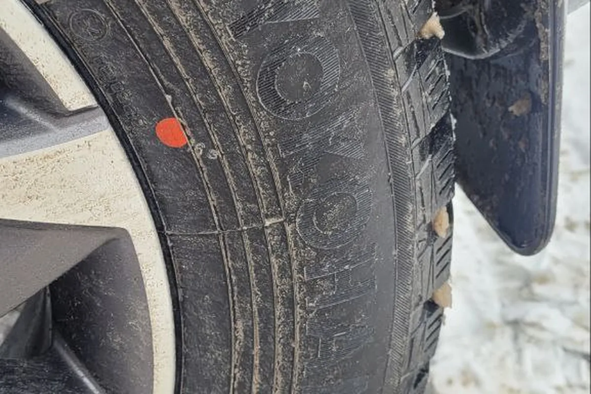 Шипованная зимняя шина на колесе Haval Dargo после поездки по льду и слякоти