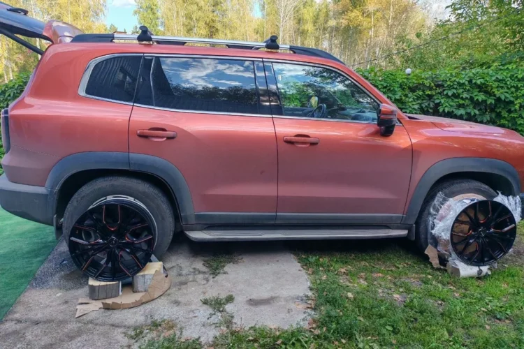 Красный Haval Dargo во время сезонной смены колёс во дворе