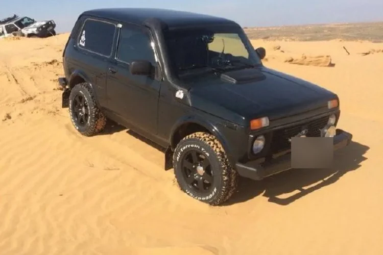 Чёрная Нива на чёрных литых дисках Слик с шинами 215/75 R15 в песках