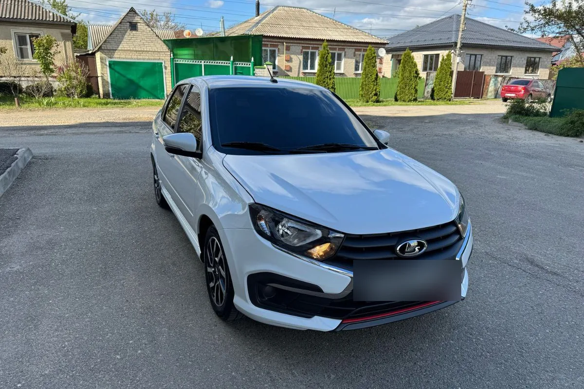 Белая Лада Гранта Drive Active с чёрной решёткой и красной полосой на бампере