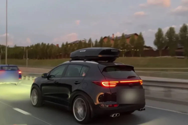 Чёрный Kia Sportage 4 с боксом на крыше на трассе вечером