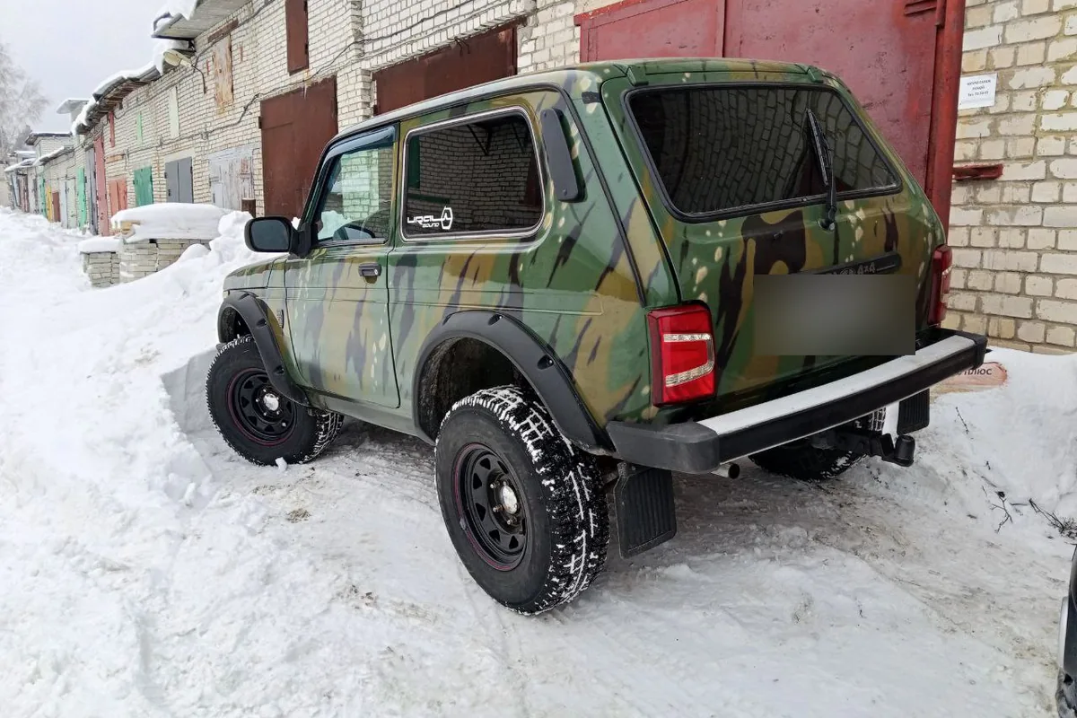 Нива Бронто 2015 года в камуфляже на штампованных дисках у гаражей зимой