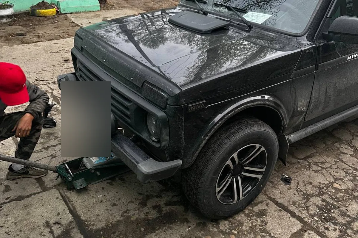 Чёрная Нива на домкрате во время переобувки, колёса на литых дисках