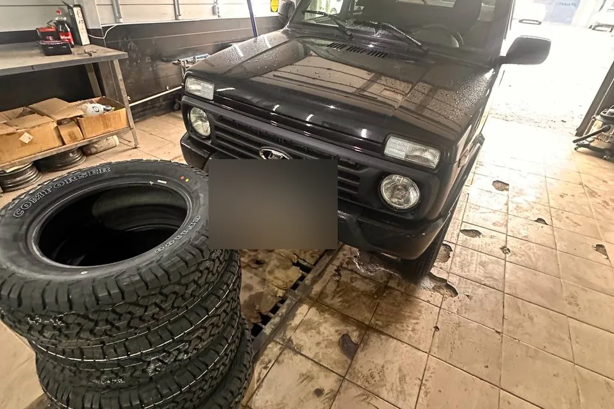 Стопка новых шин Comforser в сервисе перед чёрной Нивой