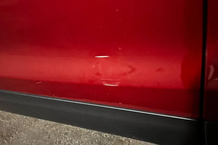 Вмятина в нижней части красной двери Nissan Qashqai J11
