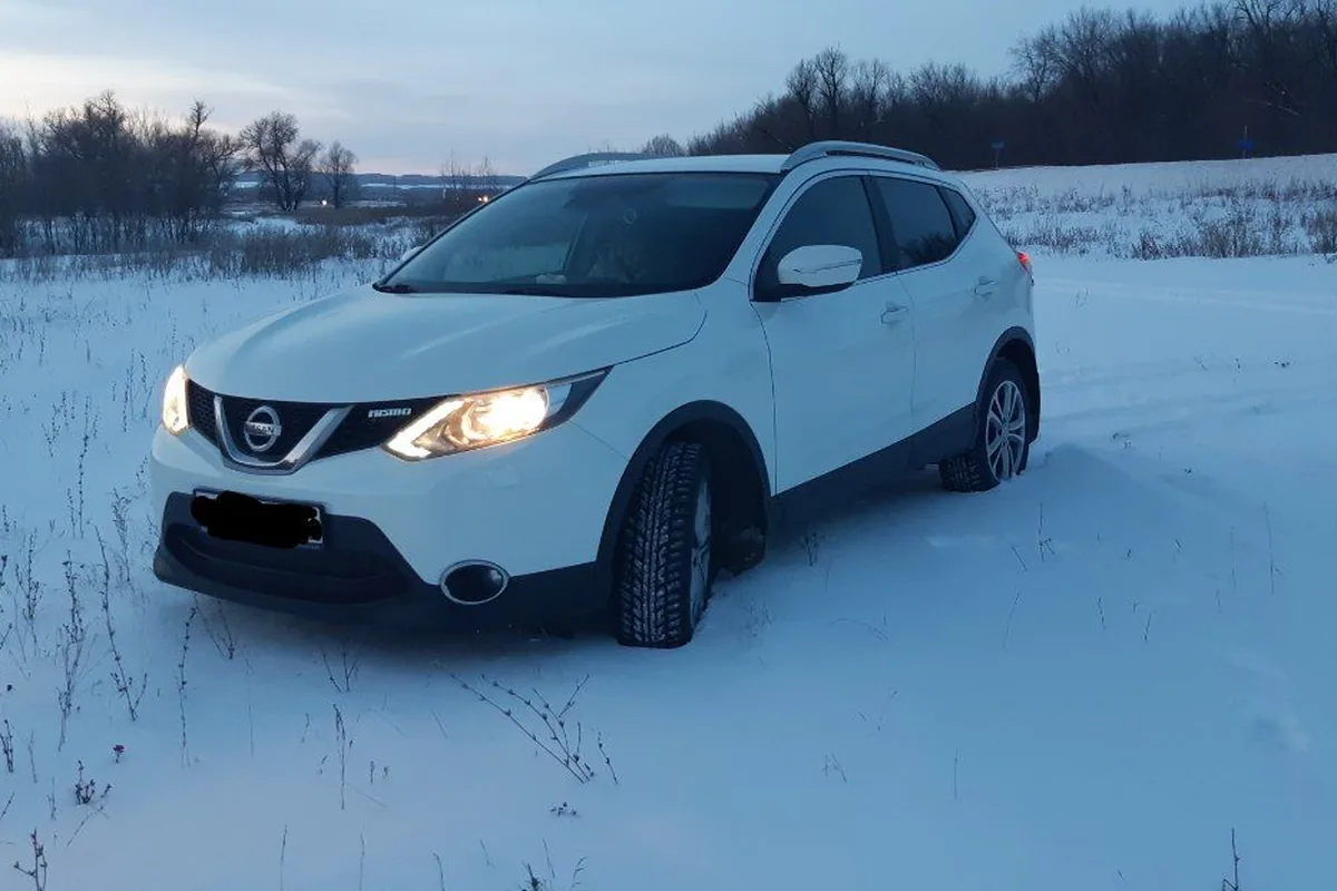 Белый Nissan Qashqai J11 2.0 с полным приводом в заснеженном поле
