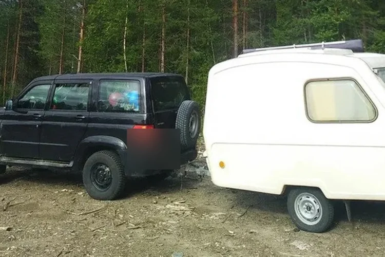 Чёрный УАЗ Патриот с жилым прицепом в лесу