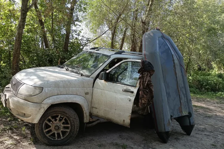 Грязный УАЗ Патриот на шинах 265/60 R18 с лодкой у двери