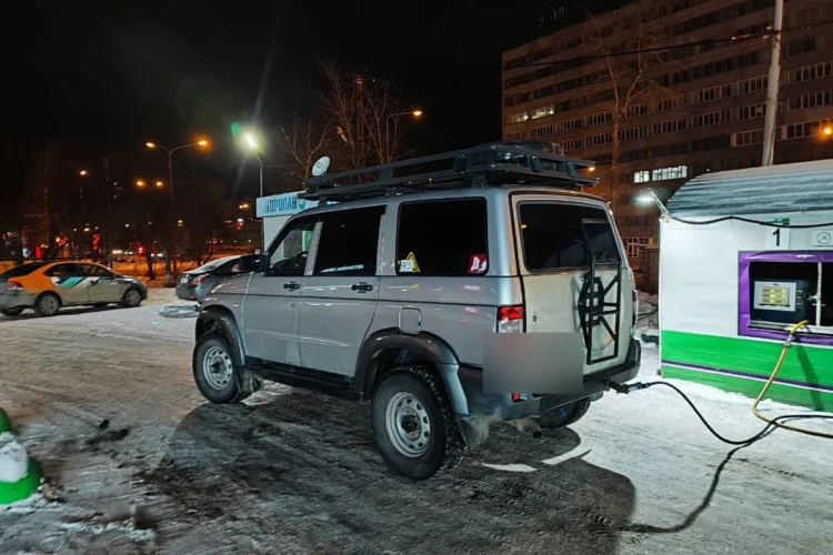 Серебристый УАЗ Патриот с багажником на крыше на заправке