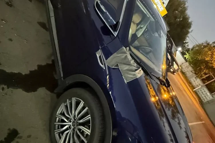 Jetour X70 Plus на подъёмнике мойки ночью