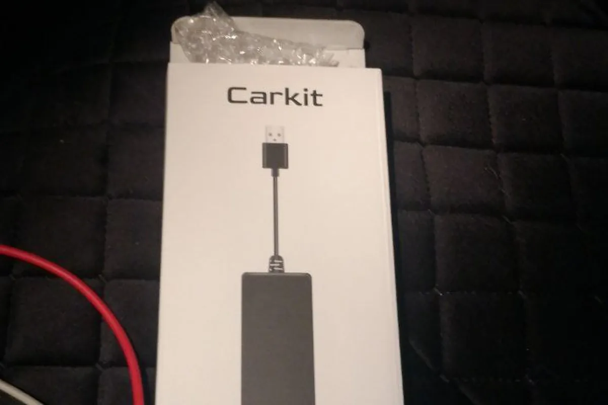 Белая коробка беспроводного адаптера Carkit лежит на черном