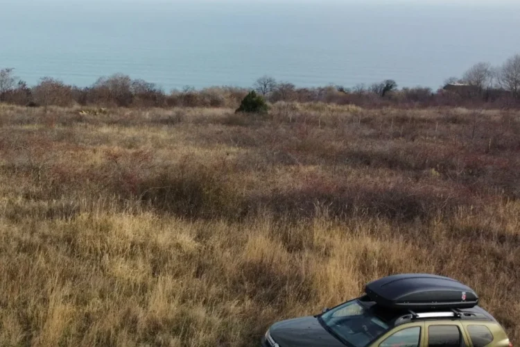 Renault Duster второго поколения с боксом на крыше у моря