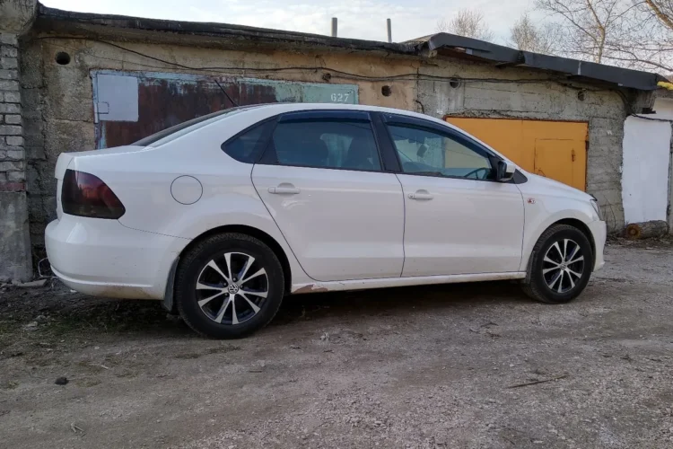 Белый Volkswagen Polo седан на литых дисках R15 сбоку