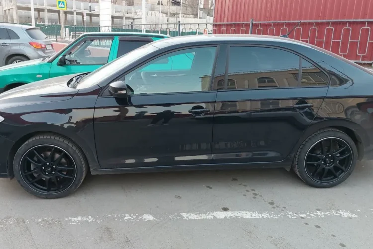 Чёрный Volkswagen Polo лифтбек на чёрных дисках R17 сбоку