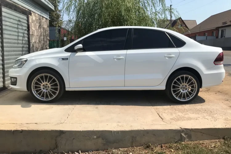 Белый Volkswagen Polo седан на литых дисках сбоку