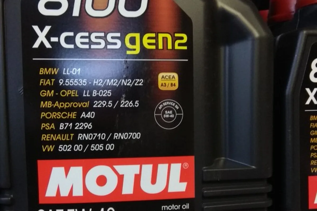 Канистры Motul 8100 X-cess 5W-40 на полке магазина с ценниками
