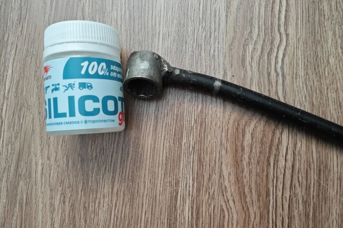 Банка силиконовой смазки Silicot и изогнутая металлическая деталь
